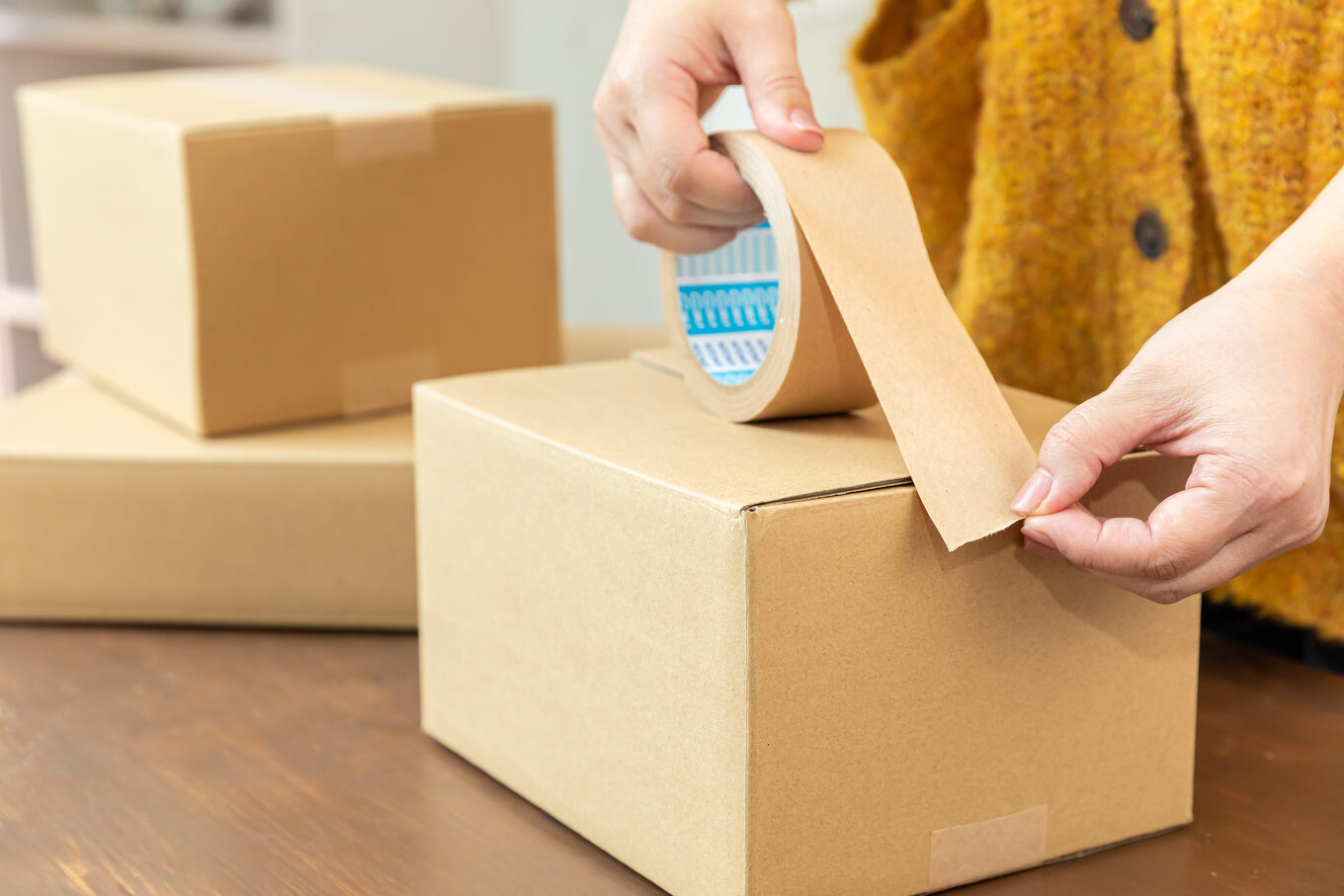 ダンボールを梱包テープで閉じる手元