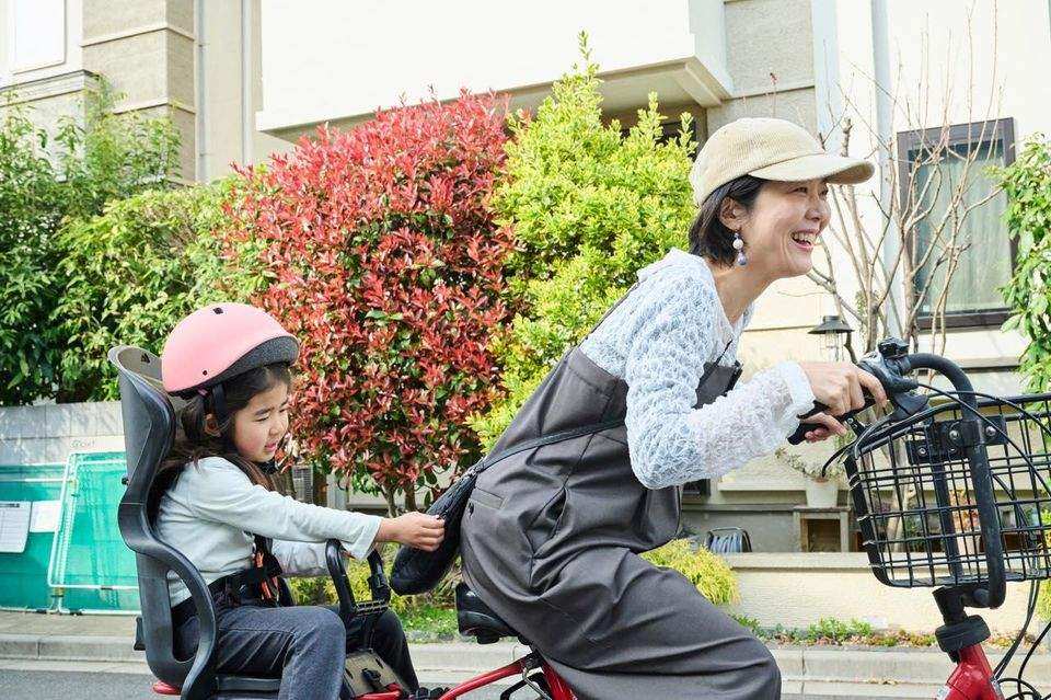 電動自転車で娘を送り迎えする母親
